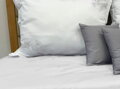 Prírodné posteľné obliečky s jemnou elegantnou výšivkou žltej farby na bielom podklade.