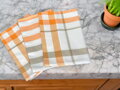 Balenie troch kusov utierok s vytkaným károvaným vzorom v oranžovej farbe.