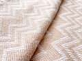 Ľahká bavlnená deka v béžovej farbe v nadčasovom vzore zig-zag. Deka môže slúžiť aj ako prehoz na gauč.