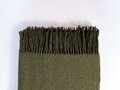 Hrejivá merino deka 140 x 200 cm z 80 % merino vlny a 20 % nylonu. Mäkká, priedušná a príjemná deka so strapcami pre pohodlný oddych doma. Olivová merino deka.