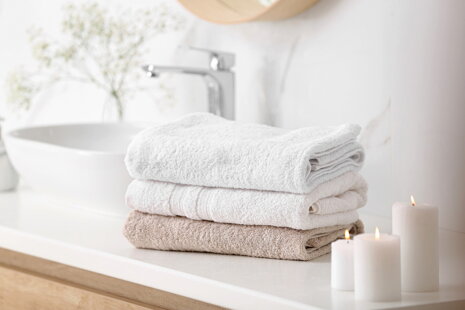 Mäkké uteráky ako z hotela Hebké biele uteráky uložené v kúpeľni na poličke, osvetlené prirodzeným svetlom | acko.sk